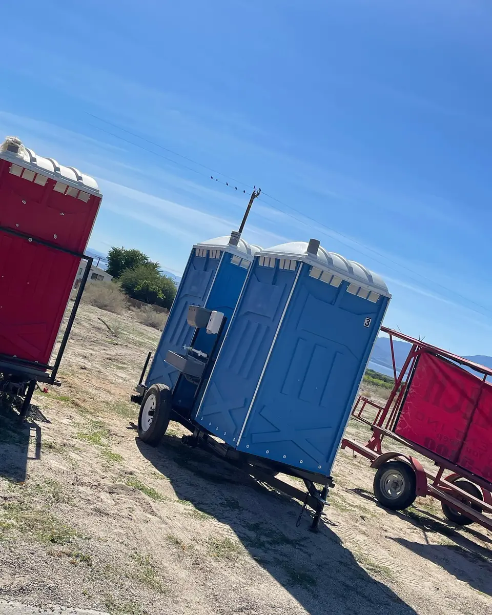 Towable porta potty trailer parked on a dirt jobsite